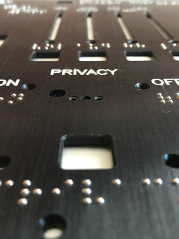 A black faceplate with white text and braille